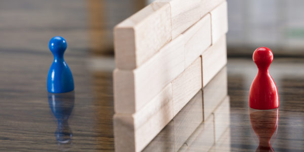 Close-up Of Red And Blue Figurine Paw Separated By Wooden Blocks On Desk