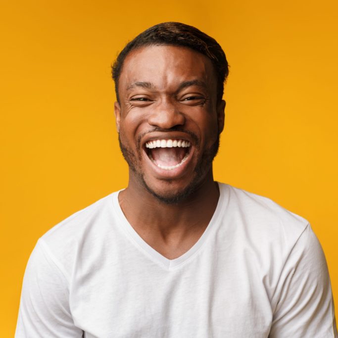 LOL. Emotional African American Man Laughing Out Loud Looking At Camera Standing In Studio Over Yellow Background.