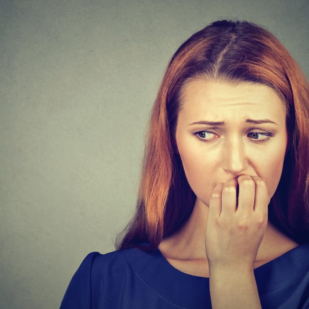 Closeup portrait young nervous woman biting her fingernails craving something or anxious, isolated on gray wall background. Negative human emotions facial expression feeling